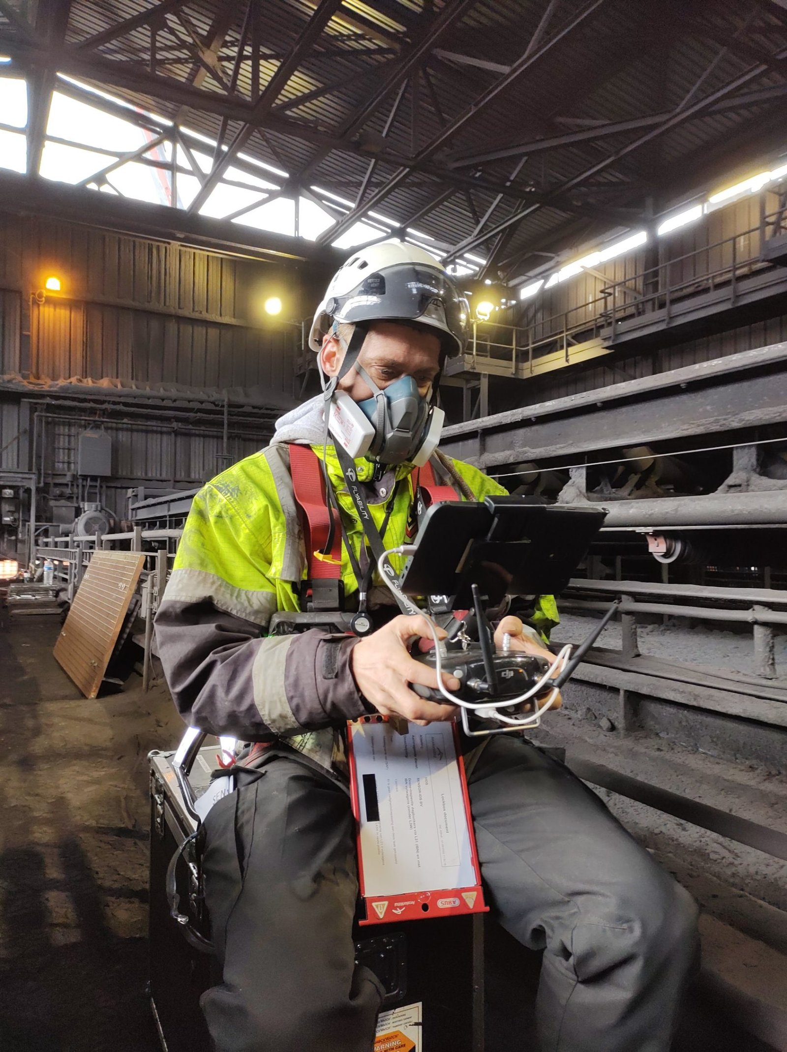 Pilot with respirator flying an indoor drone in a sinter plant