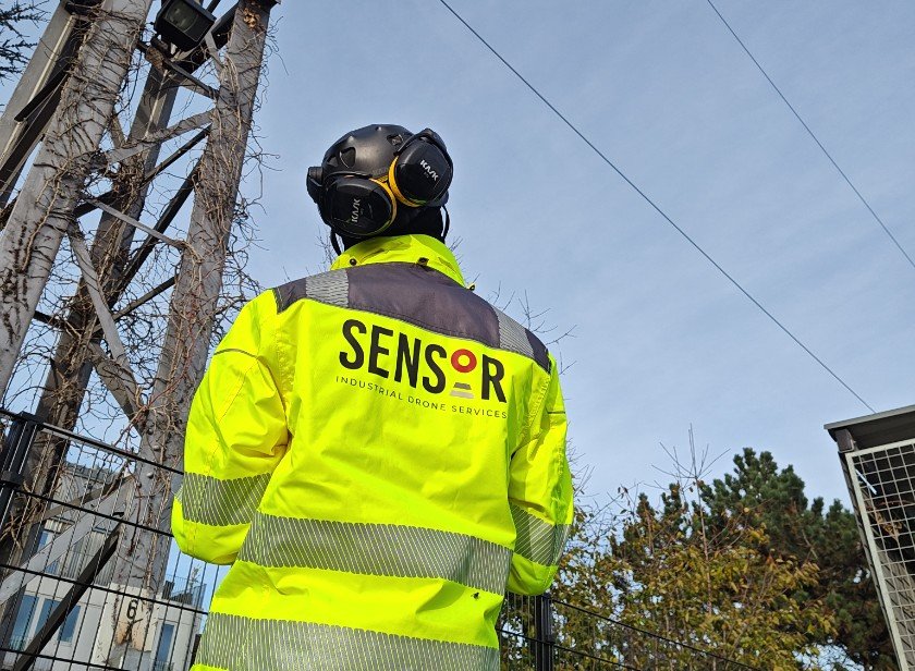Pilot flying a drone along a rail catenary mast