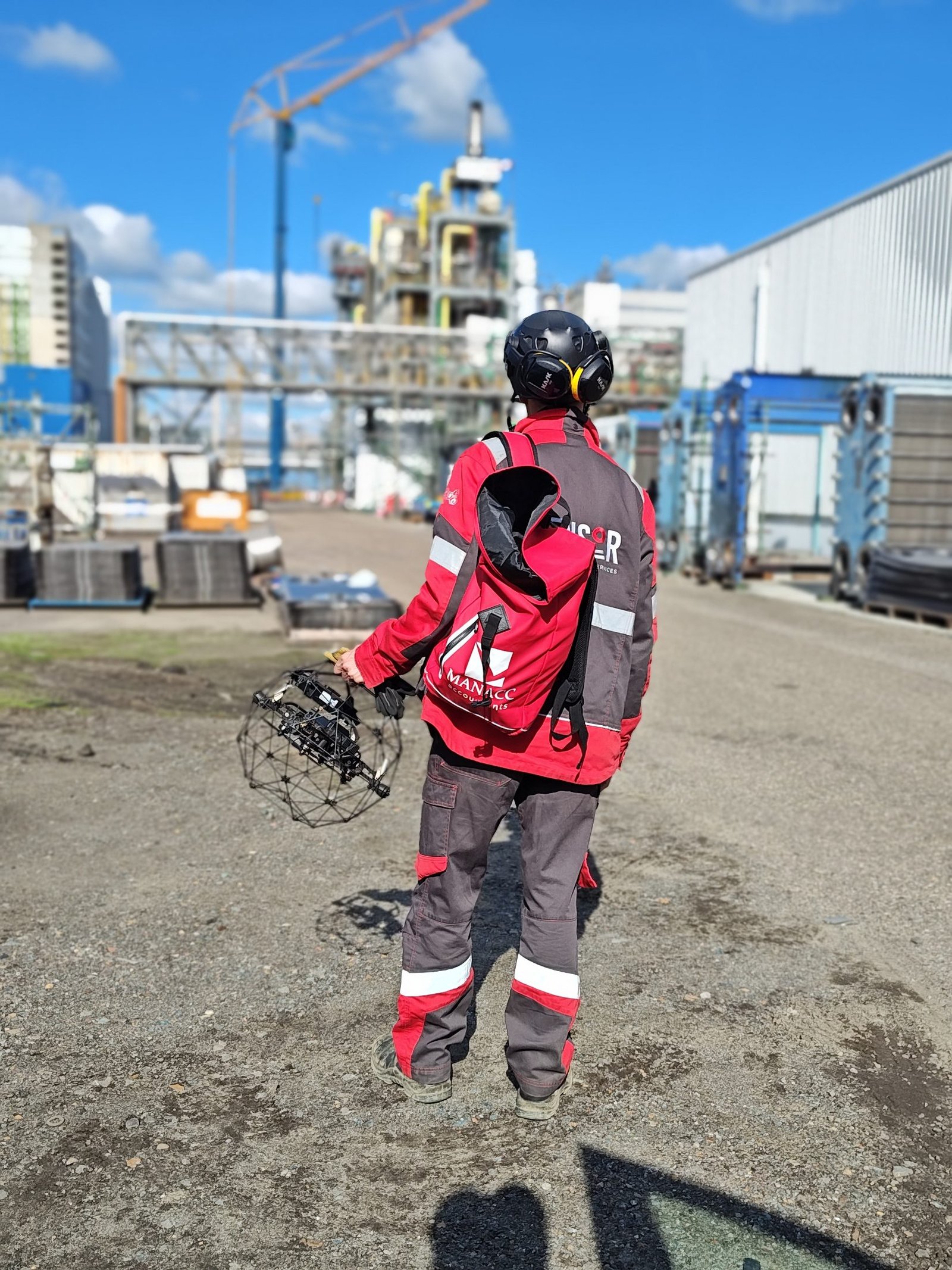 Pilot walking on site carrying a caged Elios drone
