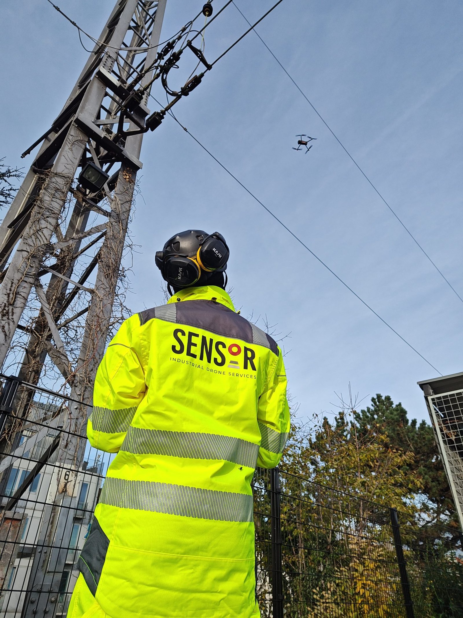 Pilot flying a drone along a rail catenary mast